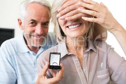 Smiling man surprising woman with a wedding ring