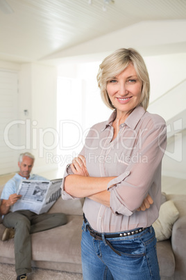 Smiling woman with man reading newspaper at home