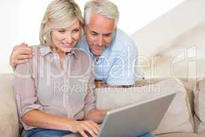 Mature couple using laptop on sofa