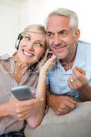 Cheerful mature couple with headphones and cellphone