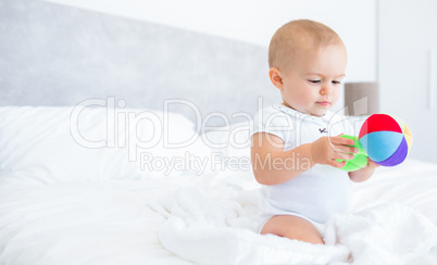 Cute baby with toy sitting on bed