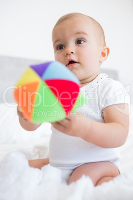 Cute baby with toy sitting on bed