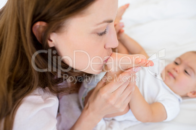 Mother kissing her babys leg on bed