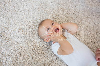 Happy cute baby lying on carpet