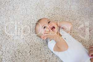 Happy cute baby lying on carpet
