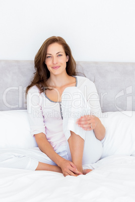 Pretty smiling young woman sitting on bed