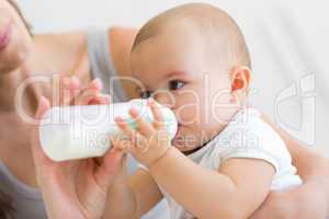 Closeup of mother feeding baby with milk bottle