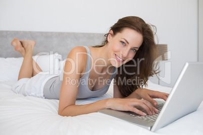 Relaxed young woman using laptop in bed