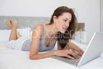 Relaxed woman using laptop in bed