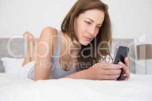 Relaxed young woman text messaging in bed