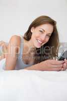 Pretty relaxed woman text messaging in bed