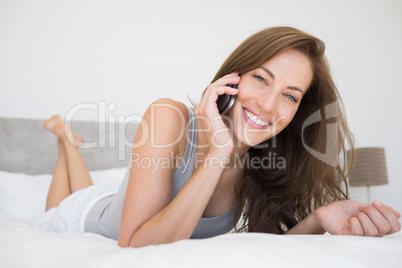 Pretty relaxed woman using mobile phone in bed