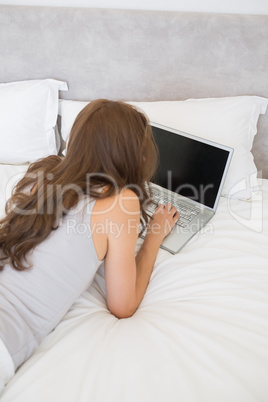 Relaxed woman using laptop in bed