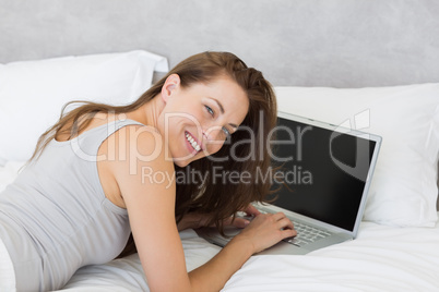 Relaxed young woman using laptop in bed