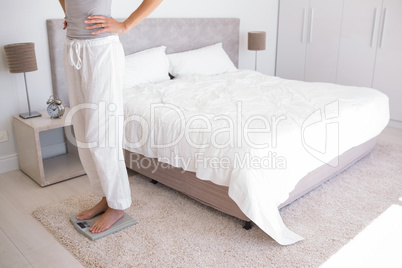 Low section of a woman standing on scale in bedroom