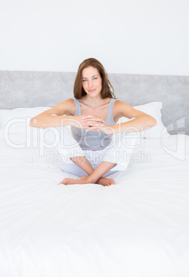 Pretty smiling young woman sitting on bed