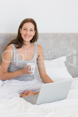 Relaxed young woman using laptop in bed