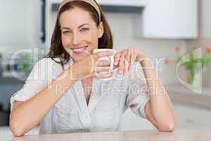 Smiling young woman with coffee cup in the kitchen