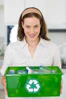 Smiling young woman carrying box with recycling symbol