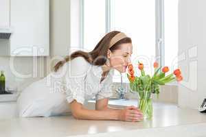 Smiling woman smelling flowers in kitchen