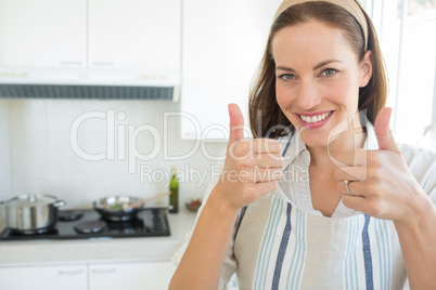 Smiling young woman gesturing thumbs up in kitchen