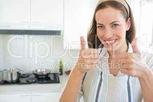Smiling young woman gesturing thumbs up in kitchen
