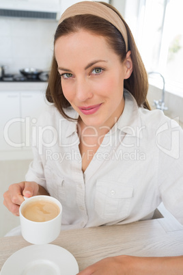 Smiling young woman with coffee cup in kitchen