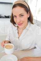 Smiling young woman with coffee cup in kitchen