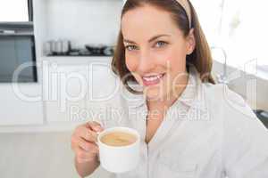 Portrait of a smiling woman with coffee cup in kitchen