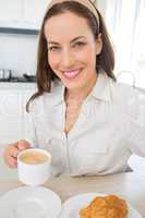 Smiling woman with coffee cup in kitchen