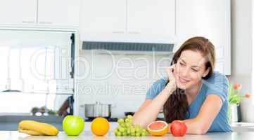 Smiling woman with fruits on counter in kitchen