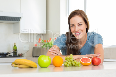 Smiling woman with fruits on kitchen counter