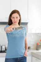 Serious woman holding out knife in kitchen