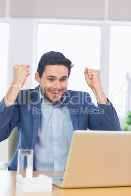 Businessman with clenched fists using laptop