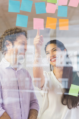 Happy businesspeople looking at adhesive notes