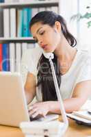 Businesswoman using laptop and telephone