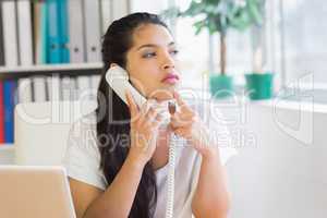 Thoughtful businesswoman using landline phone