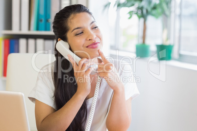 Smiling businesswoman using landline phone