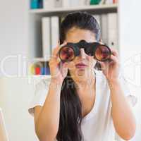 Determined businesswoman looking through binoculars