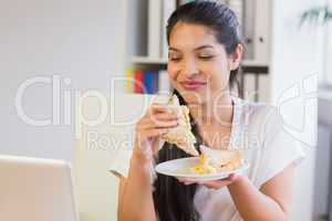 Businesswoman eating sandwich in lunch break