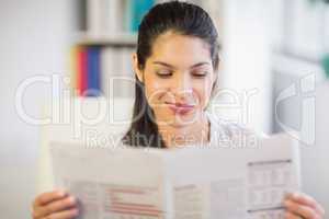 Young businesswoman reading newspaper