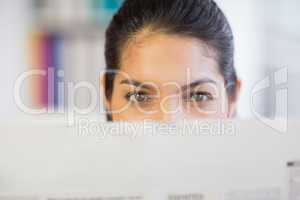 Businesswoman peeking over newspaper