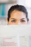 Businesswoman peeking over newspaper in office