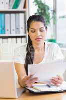 Businesswoman reading documents at desk