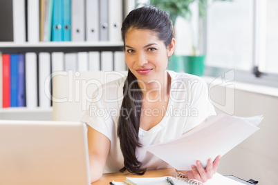businesswoman holding papers at office desk