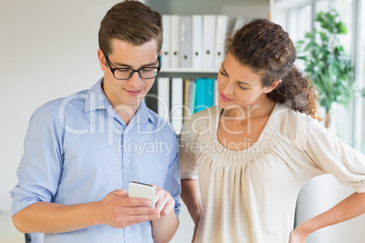 Businessman showing mobile phone to colleague