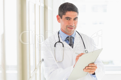 Portrait of doctor writing on clipboard