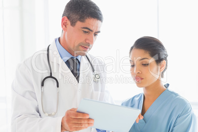 Doctor and nurse discussing over digital tablet