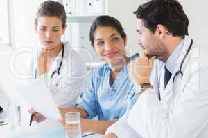 Doctors and nurse discussing over document