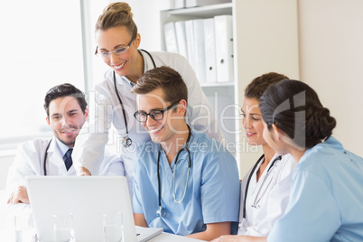 Smiling doctors and nurses discussing over laptop